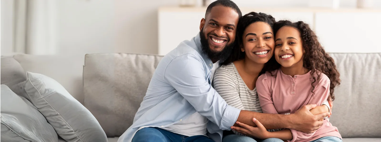 Família reunida e sorrindo no sofá de casa
