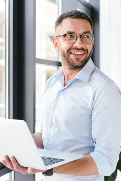 Consultor da RB2 Corretora sorrindo com um notebook em mãos